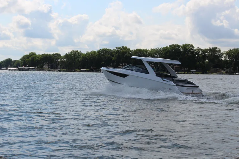 Slide: The Image of 2025 Cobalt R35 boat cruising on a scenic lake under a partly cloudy sky. - 63