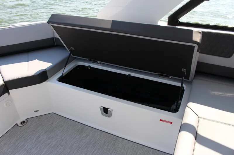Slide: The Image of Open storage compartment on 2025 Cobalt R35 boat, featuring sleek seating and water backdrop. - 66