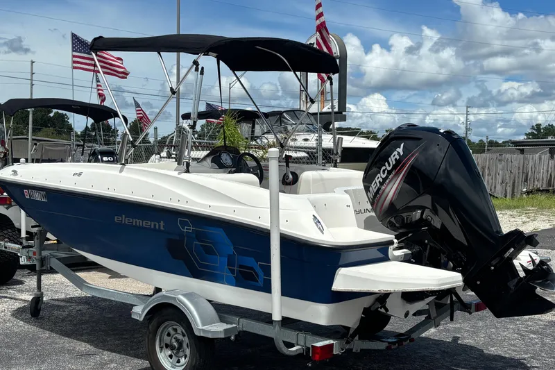 Slide: The Image of 2018 Bayliner Element E16 boat with Mercury engine on trailer, flags in background. - 3