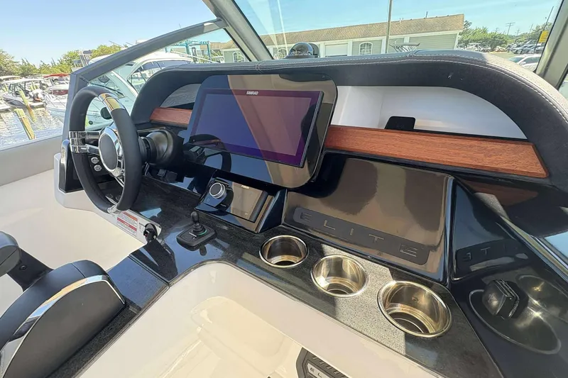 Slide: The Image of 2026 Monterey 27 Elite boat dashboard with steering wheel, touchscreen, and cup holders. - 12