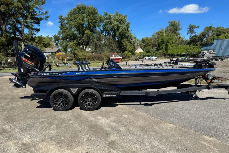 Slide: The Image of 2021 Skeeter FXR21 Apex boat on trailer, parked outdoors under clear blue sky. - 0