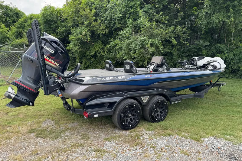 Slide: The Image of 2021 Skeeter FXR21 Apex boat with Yamaha outboard motor, parked outdoors on a sunny day. - 2
