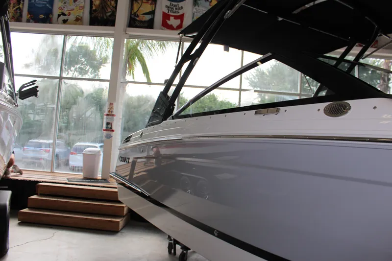 Slide: The Image of 2025 Cobalt R4 boat displayed indoors with large windows and palm trees outside. - 21