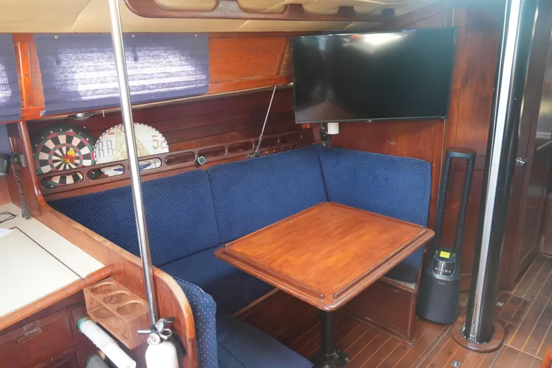 Slide: The Image of Cozy interior of 1984 Ericson 38 sailboat with blue seating, wooden table, and mounted TV. - 16