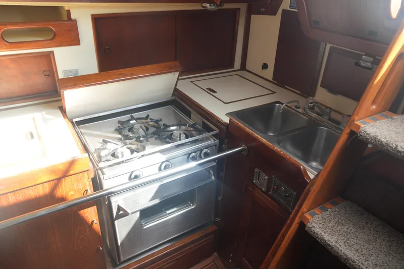 Slide: The Image of 1984 Ericson 38 yacht kitchen with stove, dual sink, and wooden cabinetry. - 19