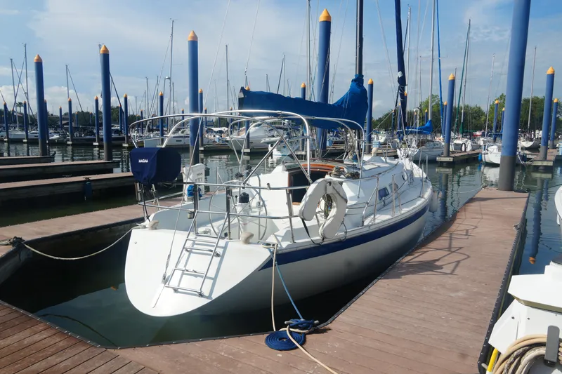 Slide: The Image of 1984 Ericson 38 sailboat docked at marina with blue sails and clear sky. - 3