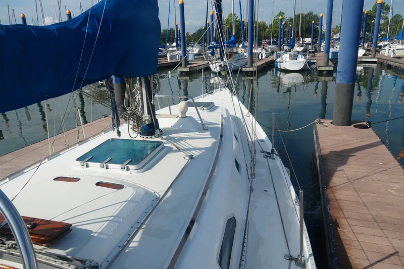 Slide: The Image of 1984 Ericson 38 sailboat docked at marina, featuring blue sail cover and calm waters. - 6