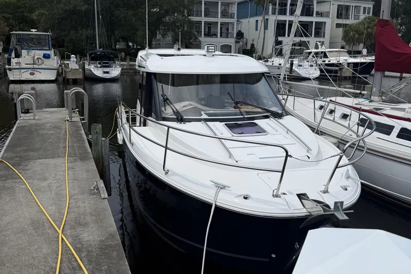 Slide: The Image of 2020 Jeanneau NC 895 boat docked at a marina, surrounded by other vessels. - 1