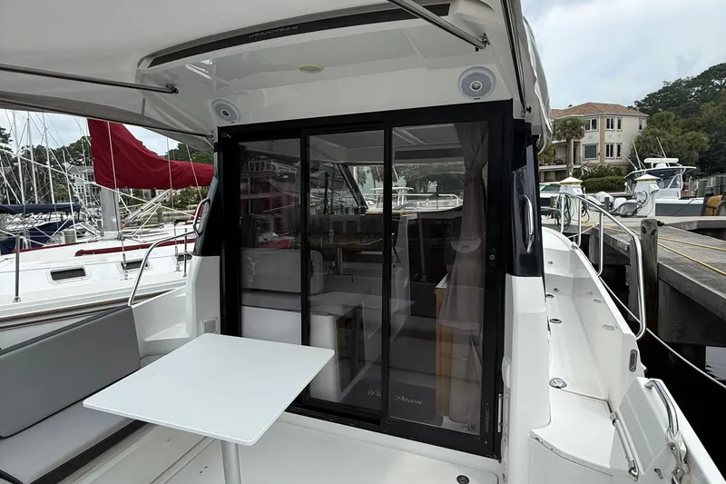 Slide: The Image of 2020 Jeanneau NC 895 boat with sliding glass doors and outdoor seating at a marina. - 11