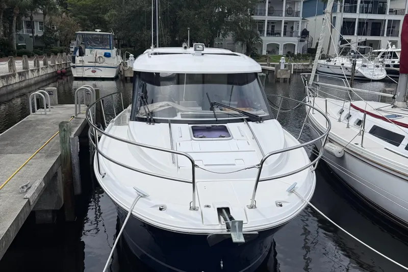 Slide: The Image of 2020 Jeanneau NC 895 boat docked at a marina, surrounded by other vessels. - 2