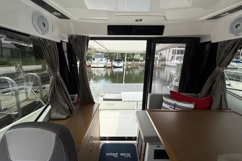 Slide: The Image of Interior view of 2020 Jeanneau NC 895 boat, featuring elegant seating and marina backdrop. - 26