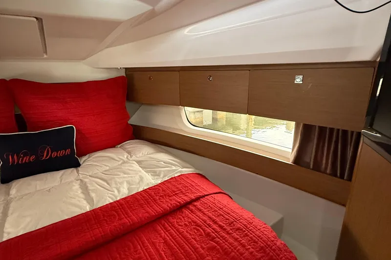 Slide: The Image of Cozy cabin interior of 2020 Jeanneau NC 895 with red bedding and wooden storage. - 33