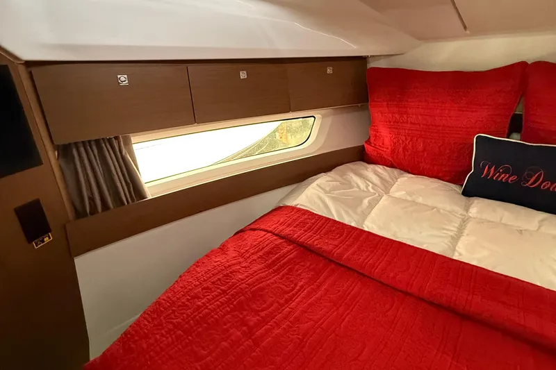 Slide: The Image of Cozy cabin interior of 2020 Jeanneau NC 895 with red bedding and window view. - 34
