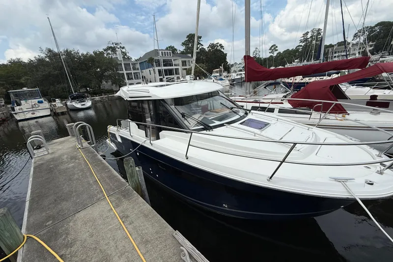 Slide: The Image of 2020 Jeanneau NC 895 boat docked at a marina with surrounding sailboats. - 4