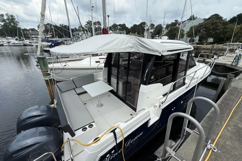 Slide: The Image of 2020 Jeanneau NC 895 boat docked, featuring a covered seating area and twin engines. - 8