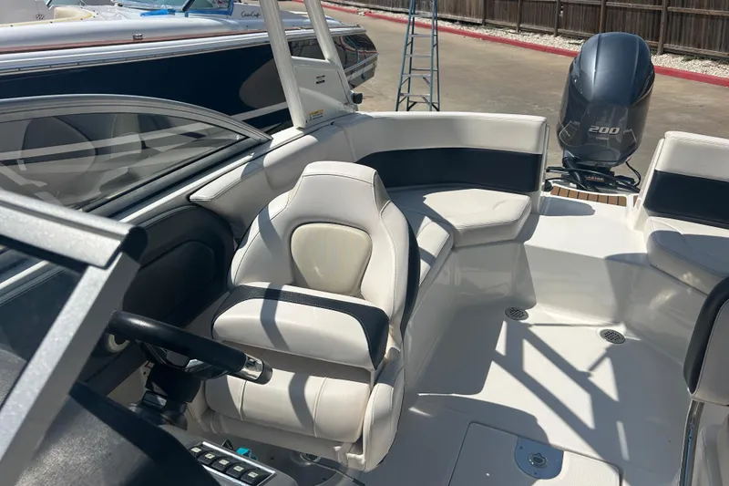 Slide: The Image of 2016 Chaparral 230 Suncoast boat interior with seating and windshield, parked outdoors. - 17
