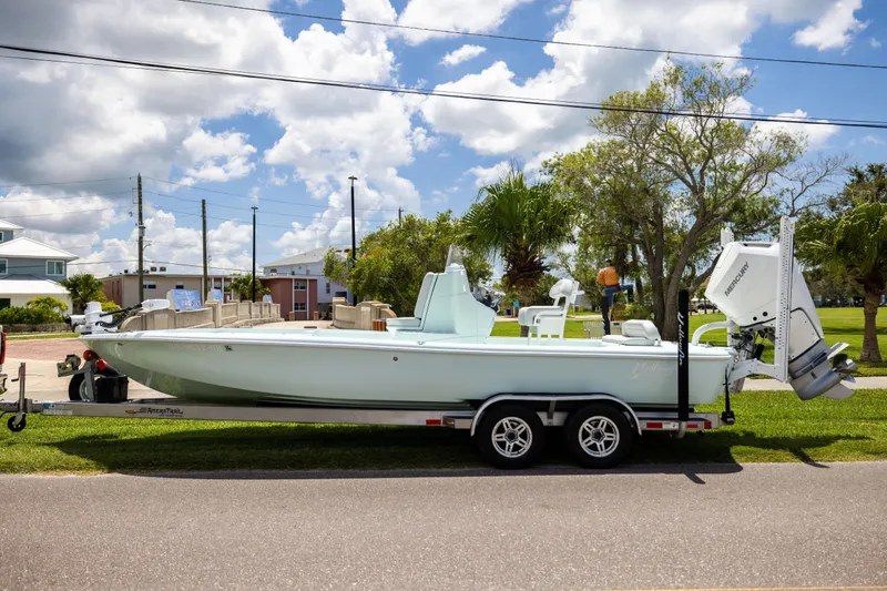 The Image of 2024 Yellowfin 24 CE boat on trailer, parked outdoors under a partly cloudy sky. - 0