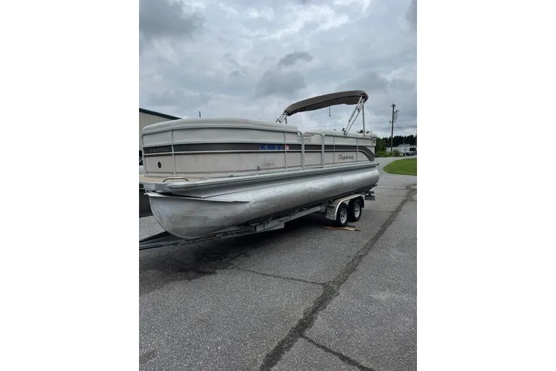The Image of 2006 Premier 225 Legend pontoon boat on trailer, parked on asphalt under cloudy sky. - 1
