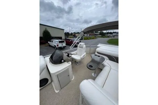 Slide: The Image of 2006 Premier 225 Legend boat interior with white seating and helm, parked outdoors. - 7