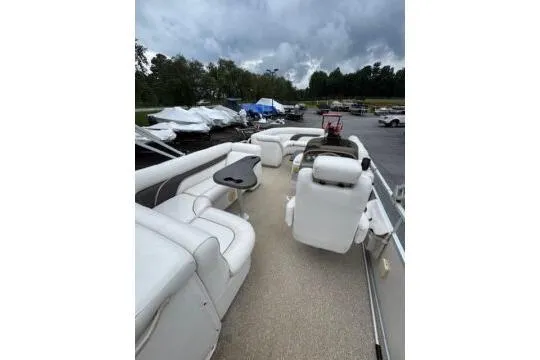 Slide: The Image of 2006 Premier 225 Legend boat with white seating and a small table, parked outdoors. - 8