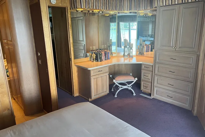 Slide: The Image of 1998 Sumerset 16x80 houseboat interior with wooden cabinetry, mirrored vanity, and cushioned stool. - 8