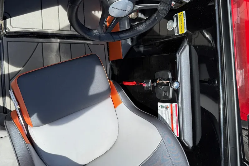 Slide: The Image of 2019 Moomba Craz boat interior with steering wheel and seat, featuring black and orange accents. - 6