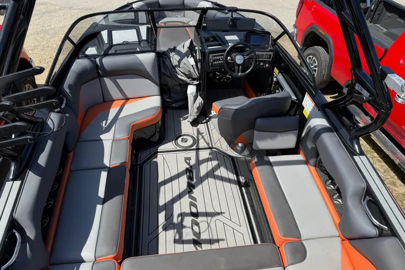 Slide: The Image of 2019 Moomba Craz boat interior with gray and orange seating, steering wheel, and dashboard. - 8