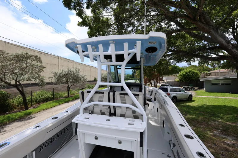 Slide: The Image of 2021 Blackfin 272 CC boat with T-top, parked outdoors under trees. - 18
