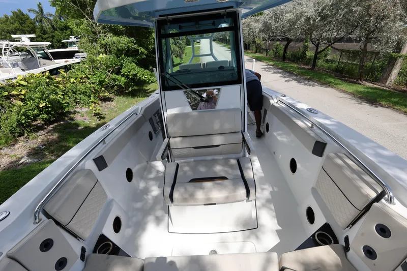 Slide: The Image of 2021 Blackfin 272 CC boat interior with seating and console, surrounded by greenery. - 23