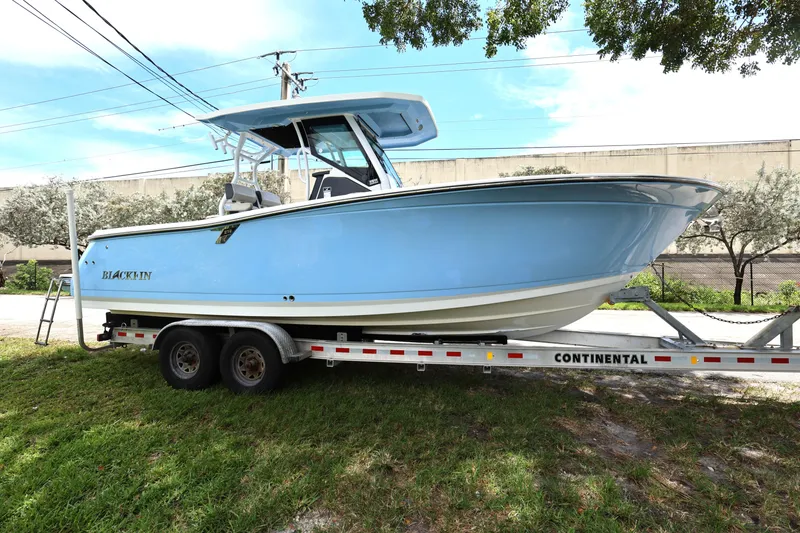 Slide: The Image of 2021 Blackfin 272 CC boat on trailer, light blue hull, parked outdoors. - 5