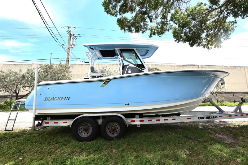 Slide: The Image of 2021 Blackfin 272 CC boat on trailer, light blue hull, parked outdoors. - 6