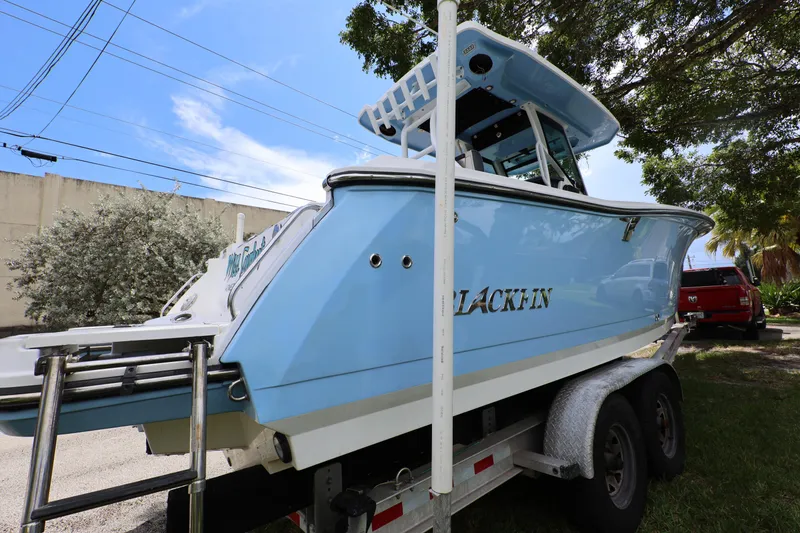 Slide: The Image of 2021 Blackfin 272 CC boat on trailer, light blue hull, parked outdoors. - 7