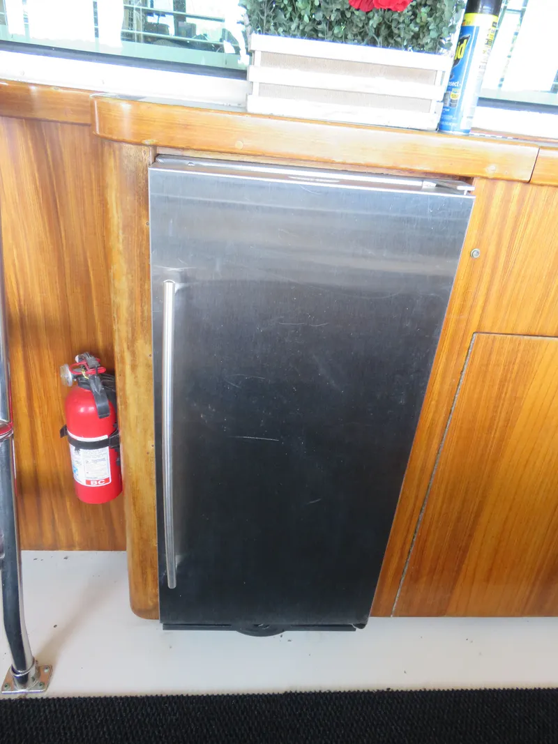Slide: The Image of Stainless steel fridge on 1986 Hatteras 58 Motor Yacht with wooden cabinetry and fire extinguisher. - 12