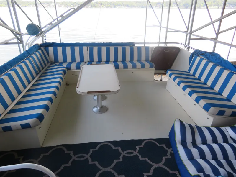 Slide: The Image of 1986 Hatteras 58 Motor Yacht interior with blue-striped seating and table, overlooking water. - 13