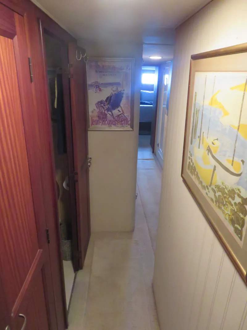 Slide: The Image of Narrow hallway inside 1986 Hatteras 58 Motor Yacht with artwork and wooden cabinets. - 28
