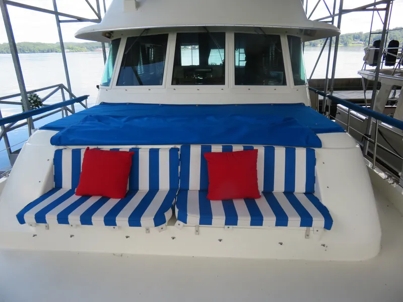 Slide: The Image of 1986 Hatteras 58 Motor Yacht with blue-striped seating and red cushions on deck. - 41