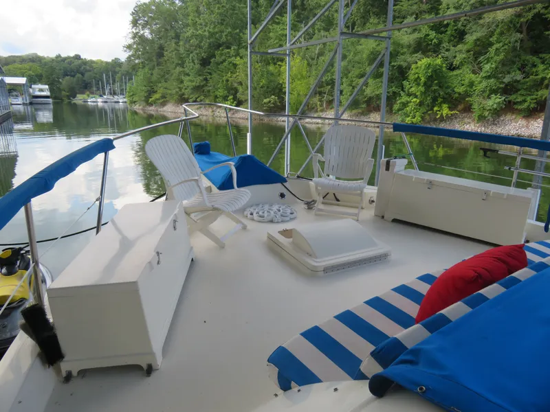 Slide: The Image of 1986 Hatteras 58 Motor Yacht deck with seating, cushions, and scenic water view. - 43