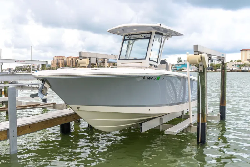 Slide: The Image of 2023 Robalo R250 Center Console boat docked on a lift in a marina setting. - 78