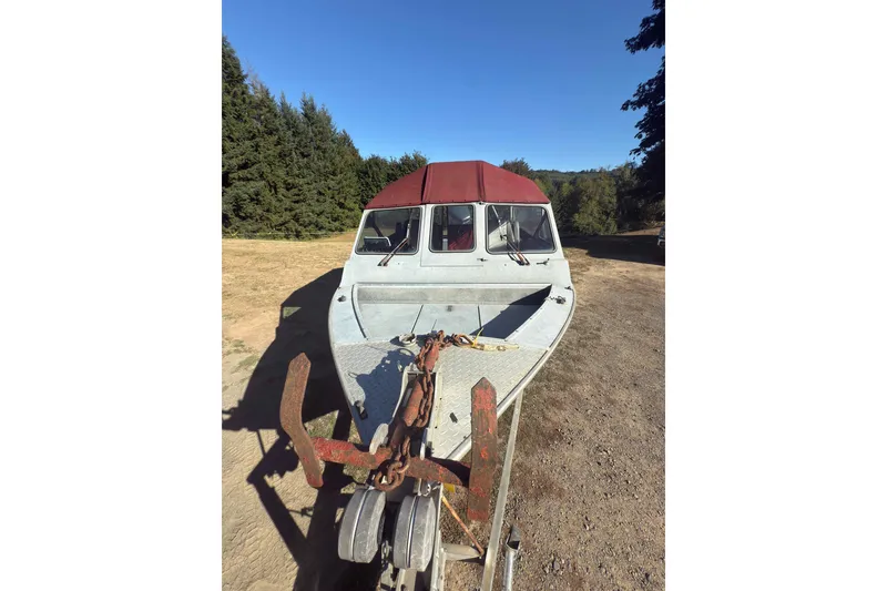 Slide: The Image of 1991 Fish Rite 22 Custom boat with red canopy, parked on a dirt path. - 23