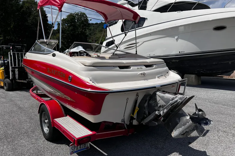 Slide: The Image of 2004 Glastron GX 185 boat with red accents on a trailer, parked outdoors. - 3