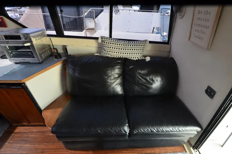 Slide: The Image of Interior of 1988 Mainship Mediterranean Convertible with black leather sofa and kitchen appliances. - 16