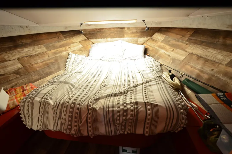 Slide: The Image of Cozy cabin interior of 1988 Mainship Mediterranean Convertible with wood paneling and striped bedding. - 17