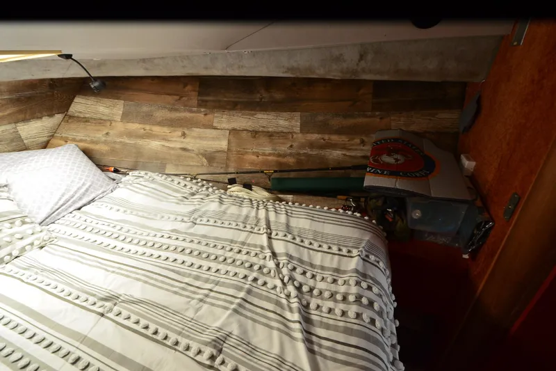 Slide: The Image of Cozy cabin interior of 1988 Mainship Mediterranean Convertible with striped bedding and wood paneling. - 19