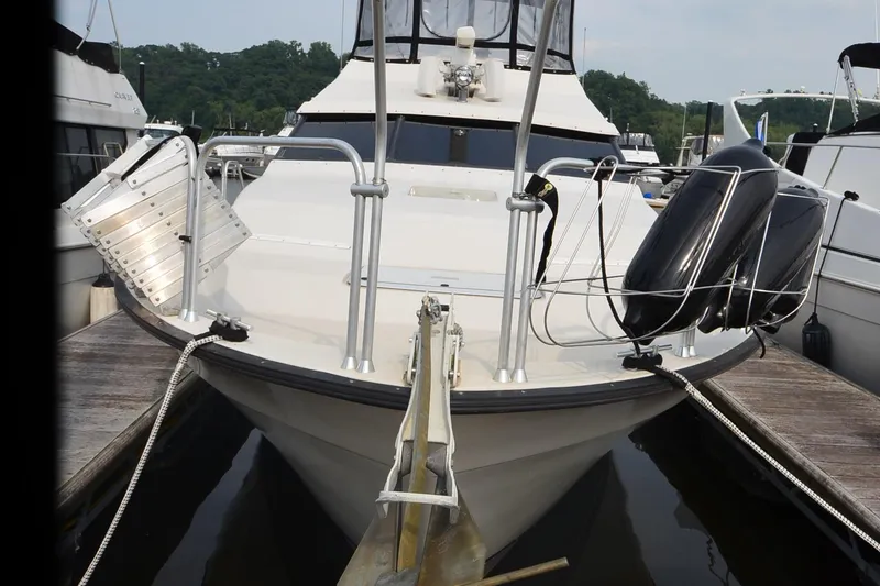 Slide: The Image of 1988 Mainship Mediterranean Convertible docked at marina, front view with fenders and ropes. - 2