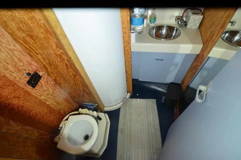 Slide: The Image of 1988 Mainship Mediterranean Convertible bathroom with sink, toilet, and wooden cabinetry. - 20
