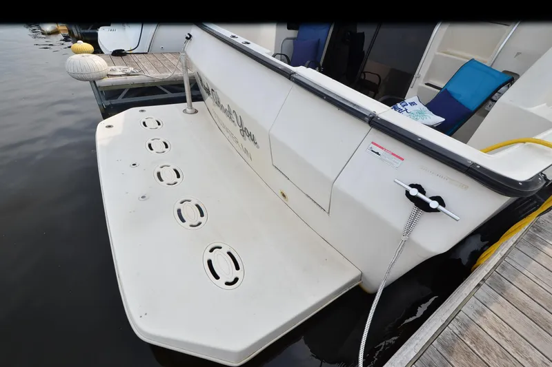 Slide: The Image of 1988 Mainship Mediterranean Convertible boat docked with swim platform and deck chairs. - 3