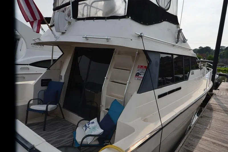 Slide: The Image of 1988 Mainship Mediterranean Convertible yacht docked, featuring outdoor seating and American flag. - 4