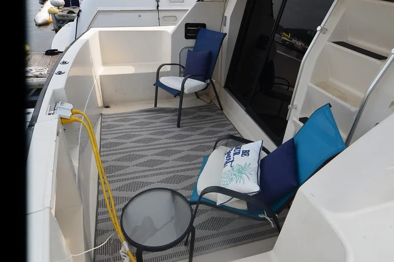 Slide: The Image of 1988 Mainship Mediterranean Convertible boat deck with chairs and table, docked at marina. - 9