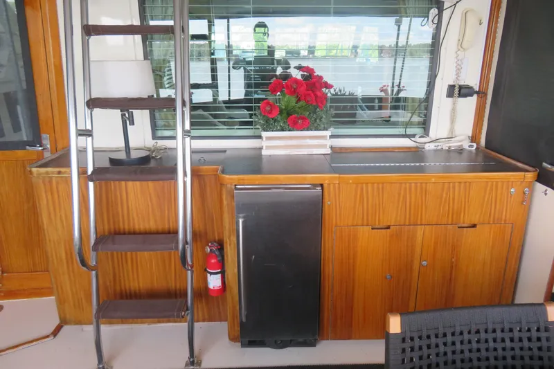 Slide: The Image of 1986 Hatteras 58 Motor Yacht interior with wooden cabinetry, ladder, and red flowers. - 11