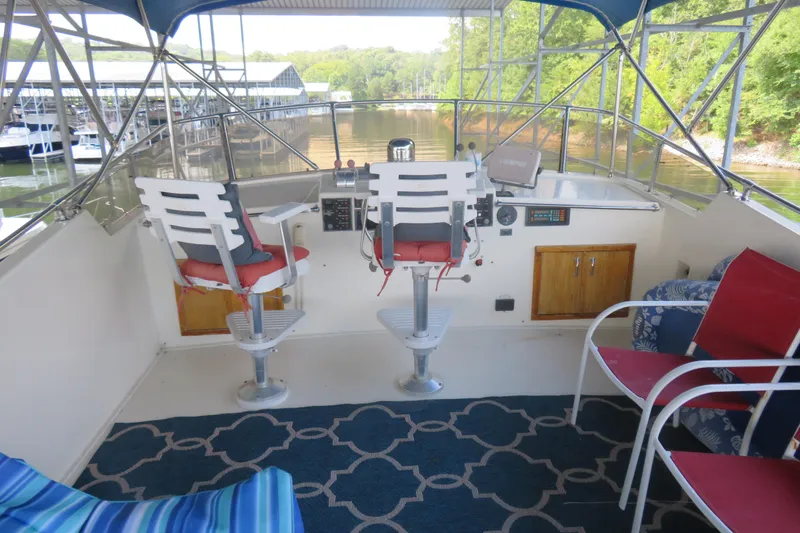 Slide: The Image of 1986 Hatteras 58 Motor Yacht helm with seating, overlooking marina and lush greenery. - 15
